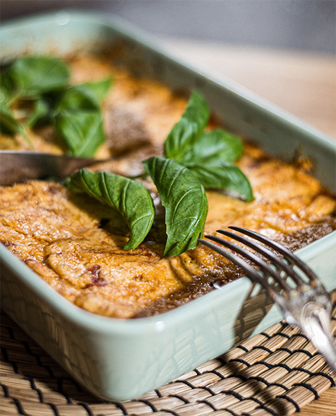 Image, Vous pouvez voir un bol de lasagnes avec une casserole décorée de basilic et un cordon posé sur le bord du bol.