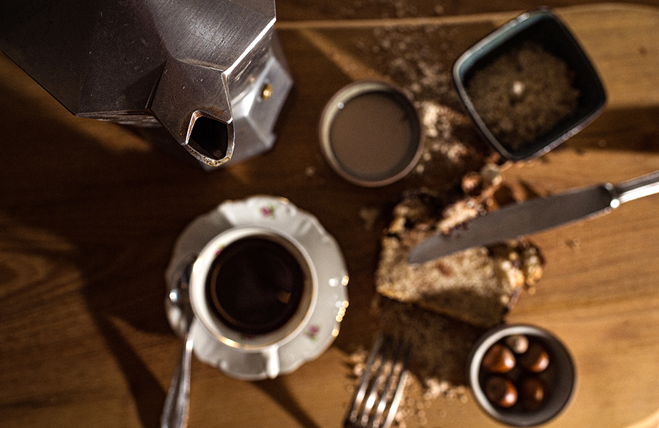 Image, Composition d'une cafetière, tasse à café, bol avec café en poudre, un bol avec des noix et une tranche de pain avec un couteau dessus.