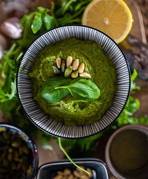 Image, Vue de dessus d'un bol avec un pesto classique, décoré de basilic, de pignons de pin et d'un citron.