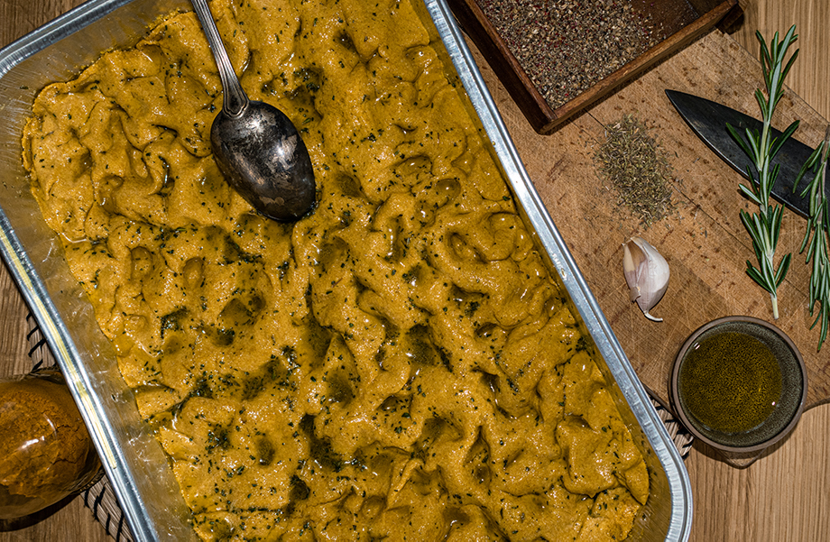 Image, Vue de dessus d'un bol de curcuma focaccia. Un couteau et une gousse d'ail se tiennent à côté du bol