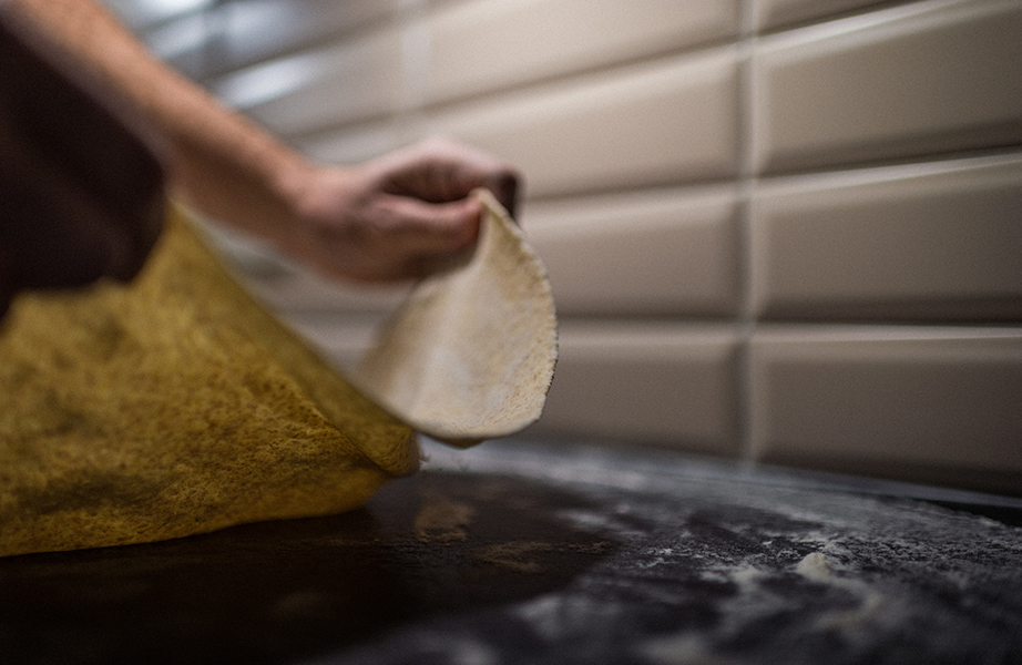 Image, Un chef Rucolino étale la pâte dans sa cuisine. Le gâteau fait tourner la pâte, la pâte roulée n'est qu'à moitié sur l'assiette lorsqu'elle est ramassée.